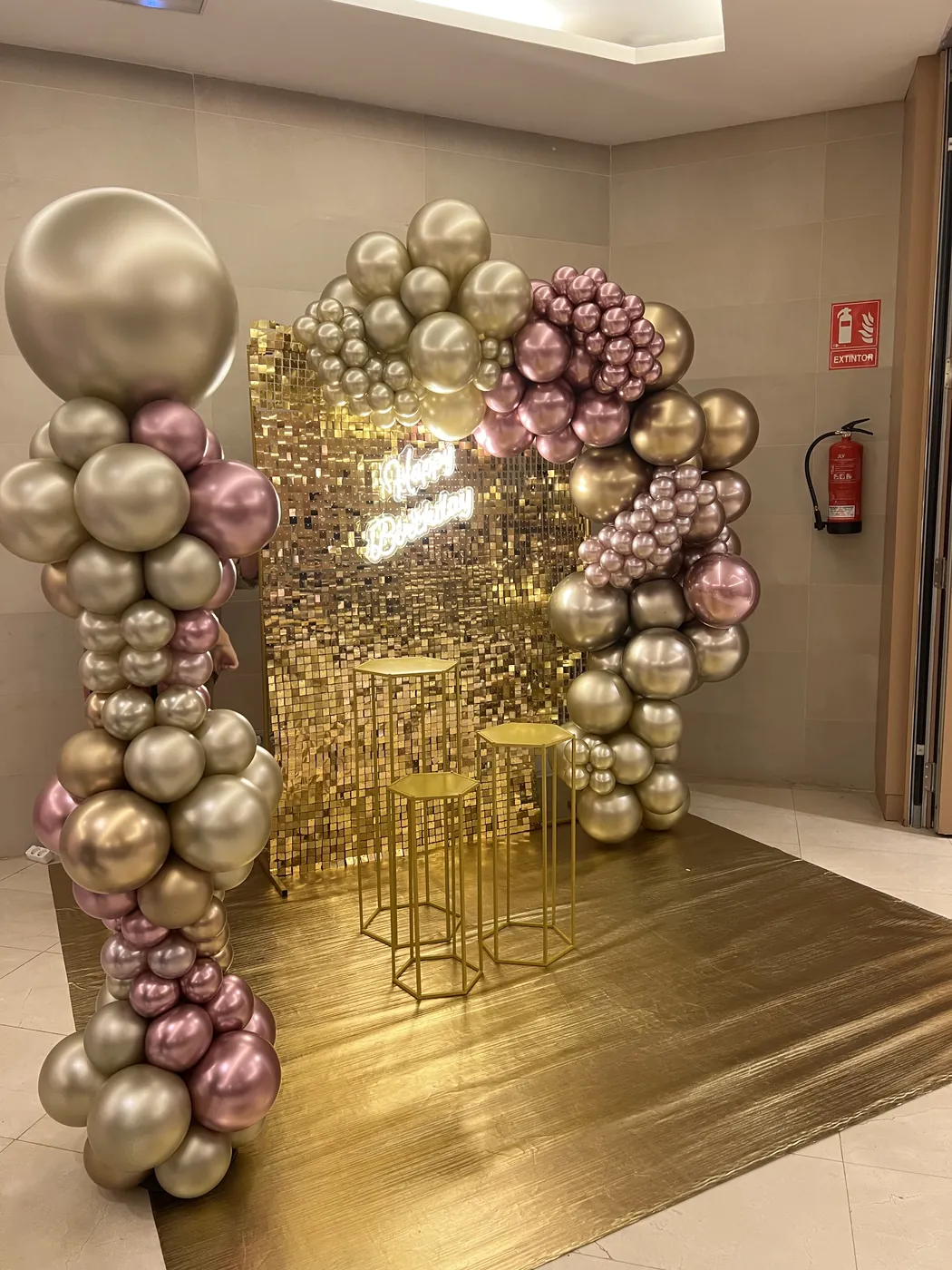 Gold and rose balloon installation framing a sequin backdrop