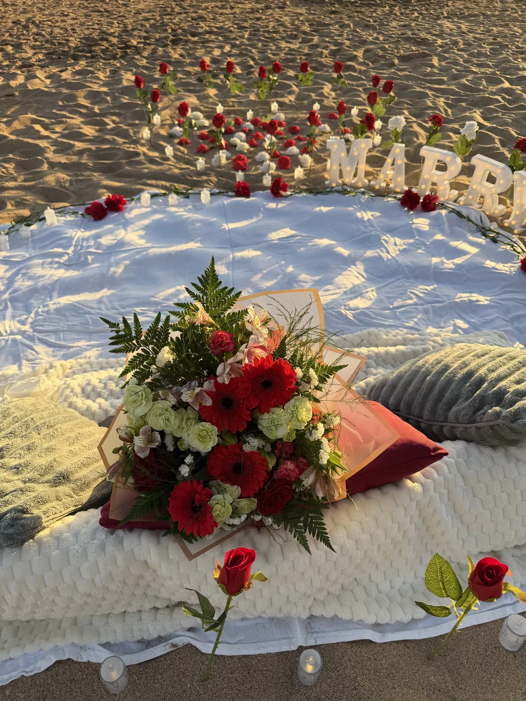 Fresh bouquet resting on cushions at a beach picnic setup
