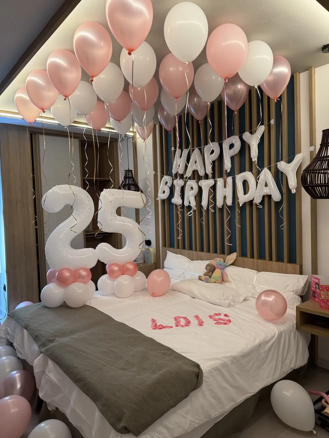 Hotel room decorated with pink balloons for a 25th birthday