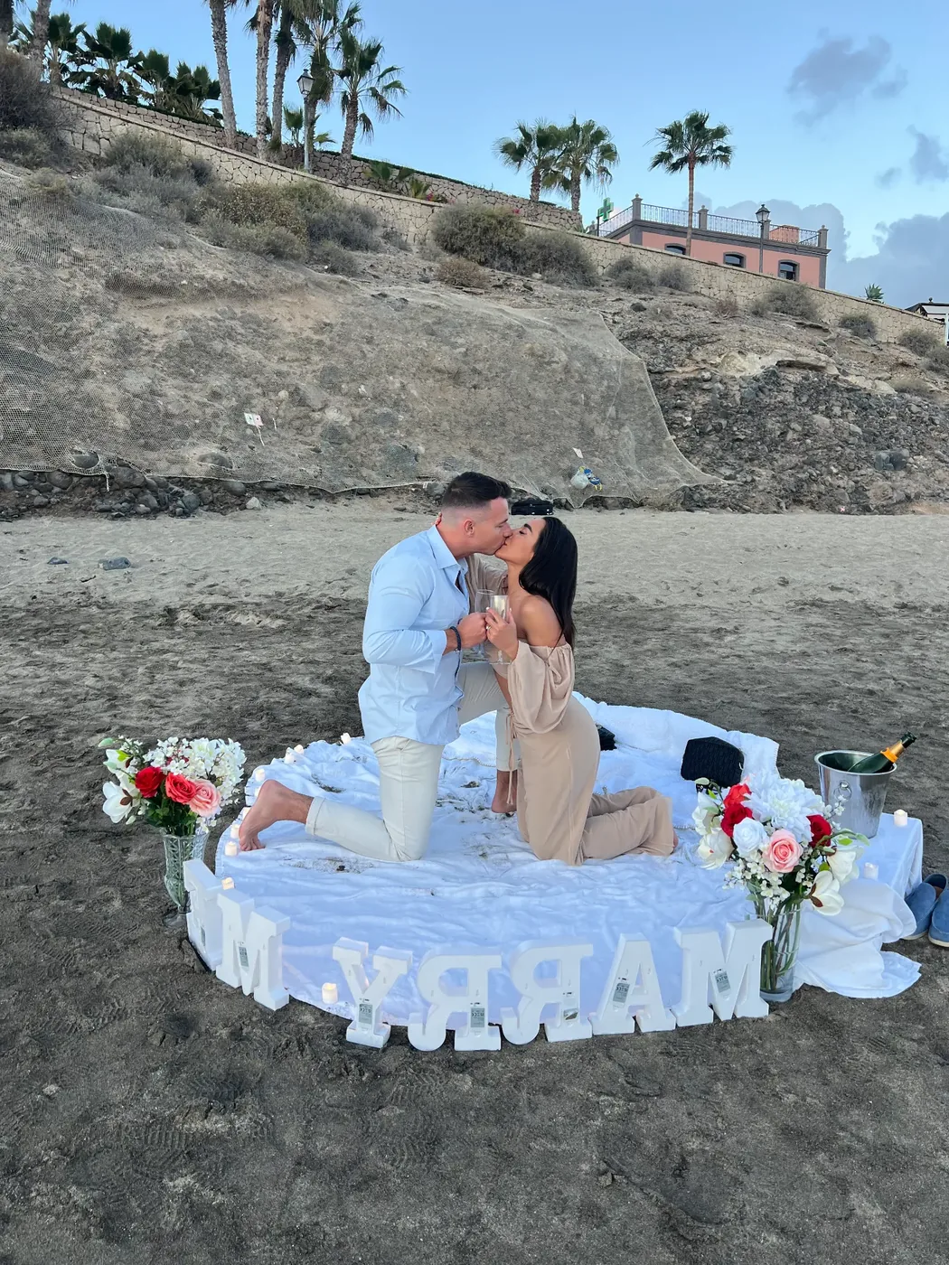 A proposal at a styled Eventissimo beach picnic, with fresh flowers and champagne